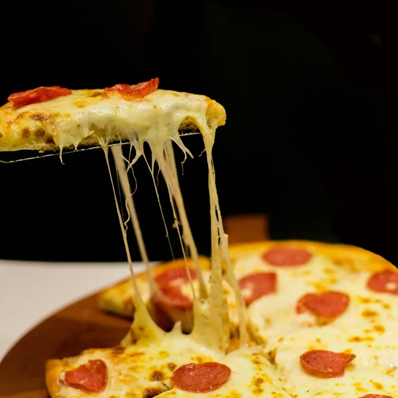Cheese pull from a slice of pepperoni pizza